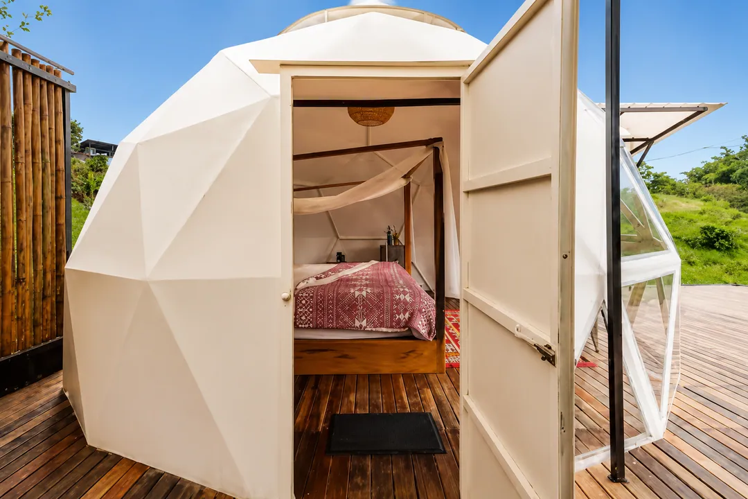 Puerta abierta del Domo Papiros con vista a la cama con dosel y mosquitero