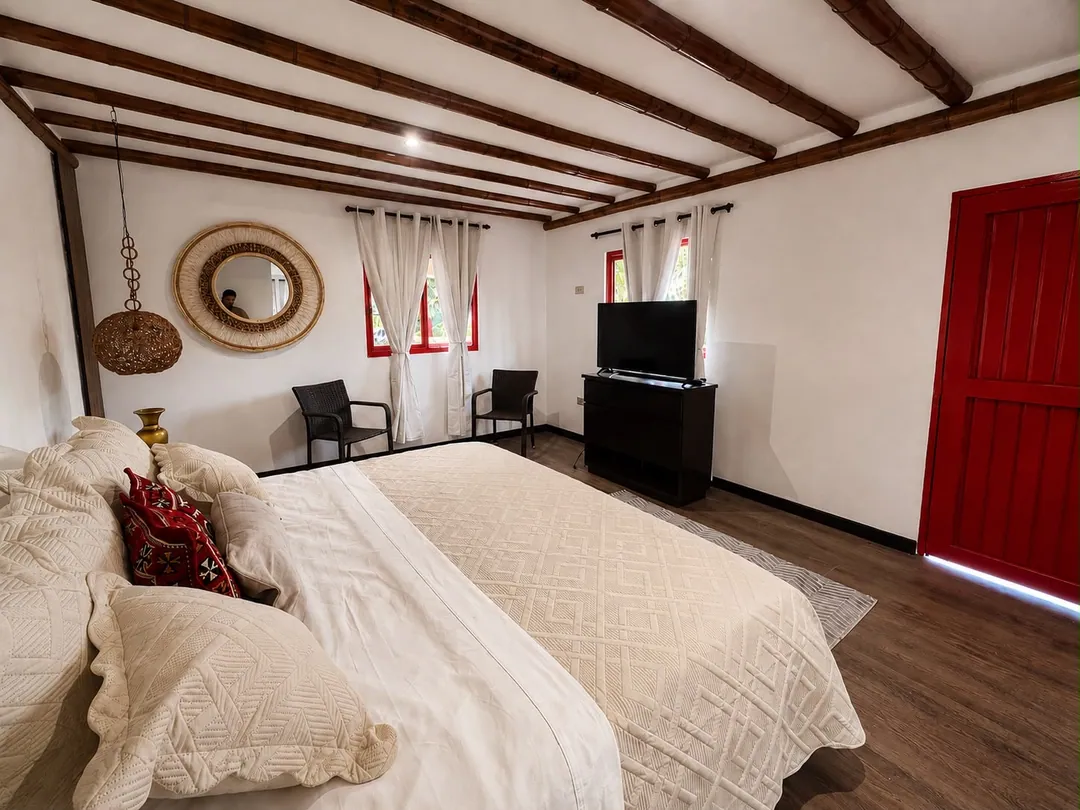 Dormitorio de la Suite Aullador con vigas de madera, cama King y puerta roja