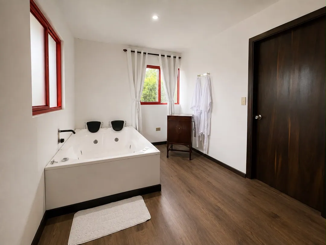 Jacuzzi con hidromasaje y batas de baño junto a la ventana en la Suite Aullador