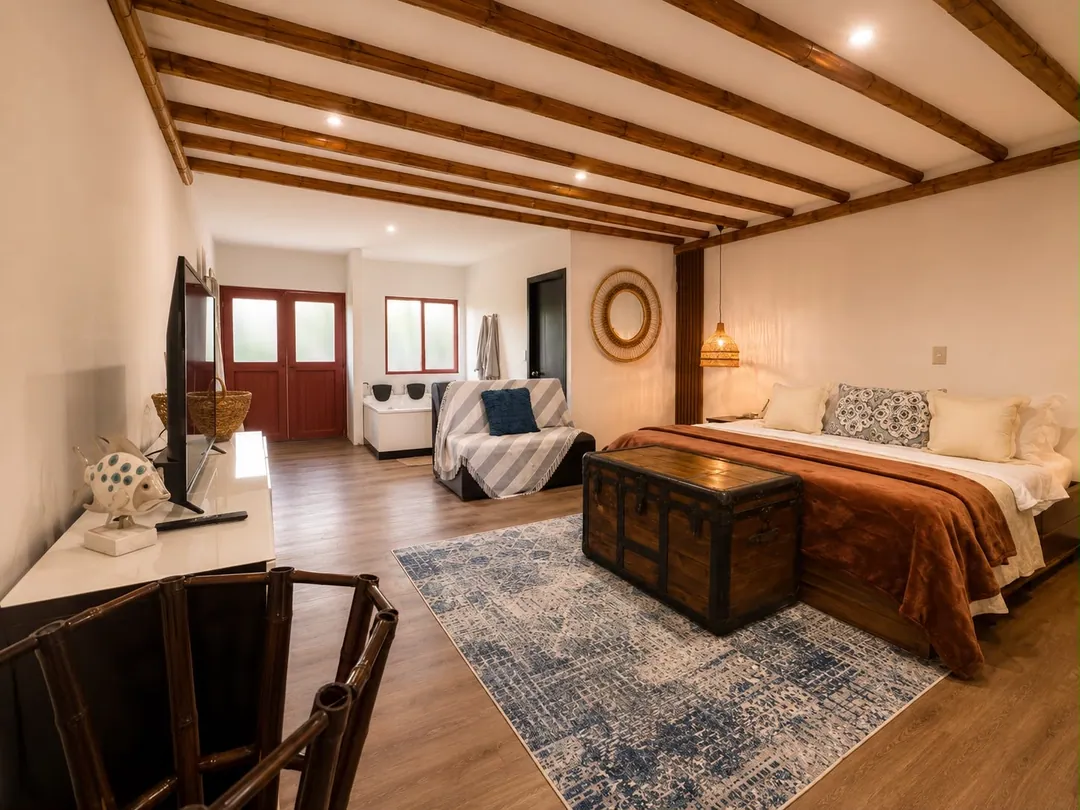 Dormitorio de la Suite Barranquero con cama King, baúl de madera y alfombra azul