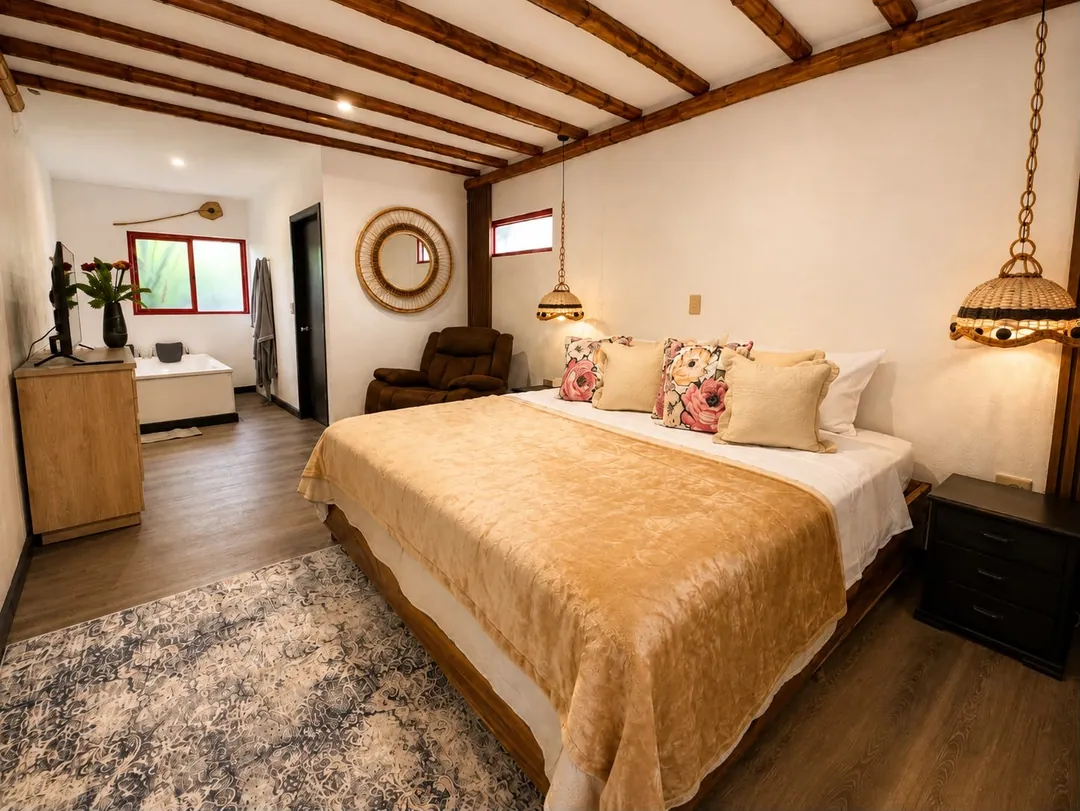 Dormitorio de la Suite Colibrí con cama King, vigas de madera y lámparas tejidas