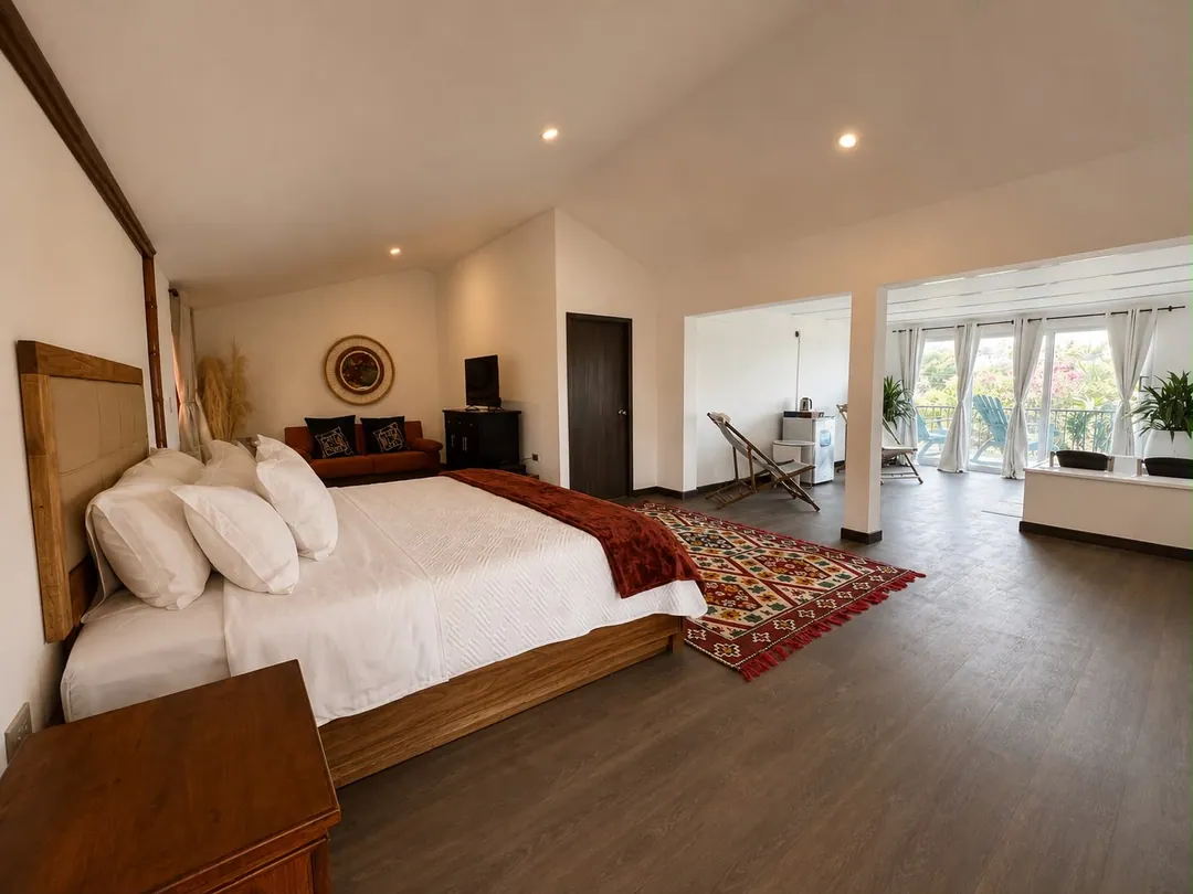 Dormitorio amplio de la Suite Quimbaya con cama King, alfombra tejida y ventanales