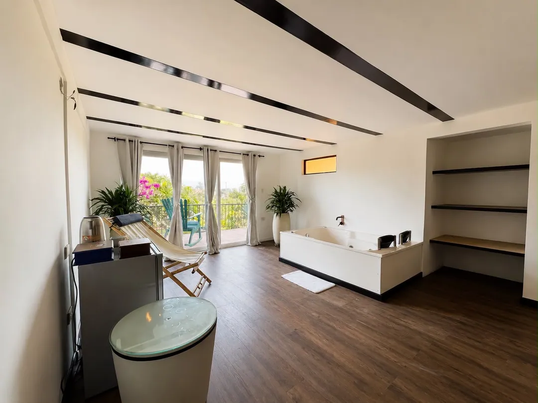 Sala con jacuzzi, hamaca y ventanales con vista al jardín en la Suite Quimbaya
